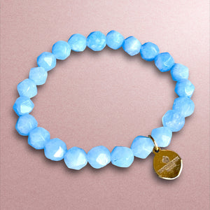 bracelet femme pierre naturelle agate bleue avec breloque - fond beige de pres